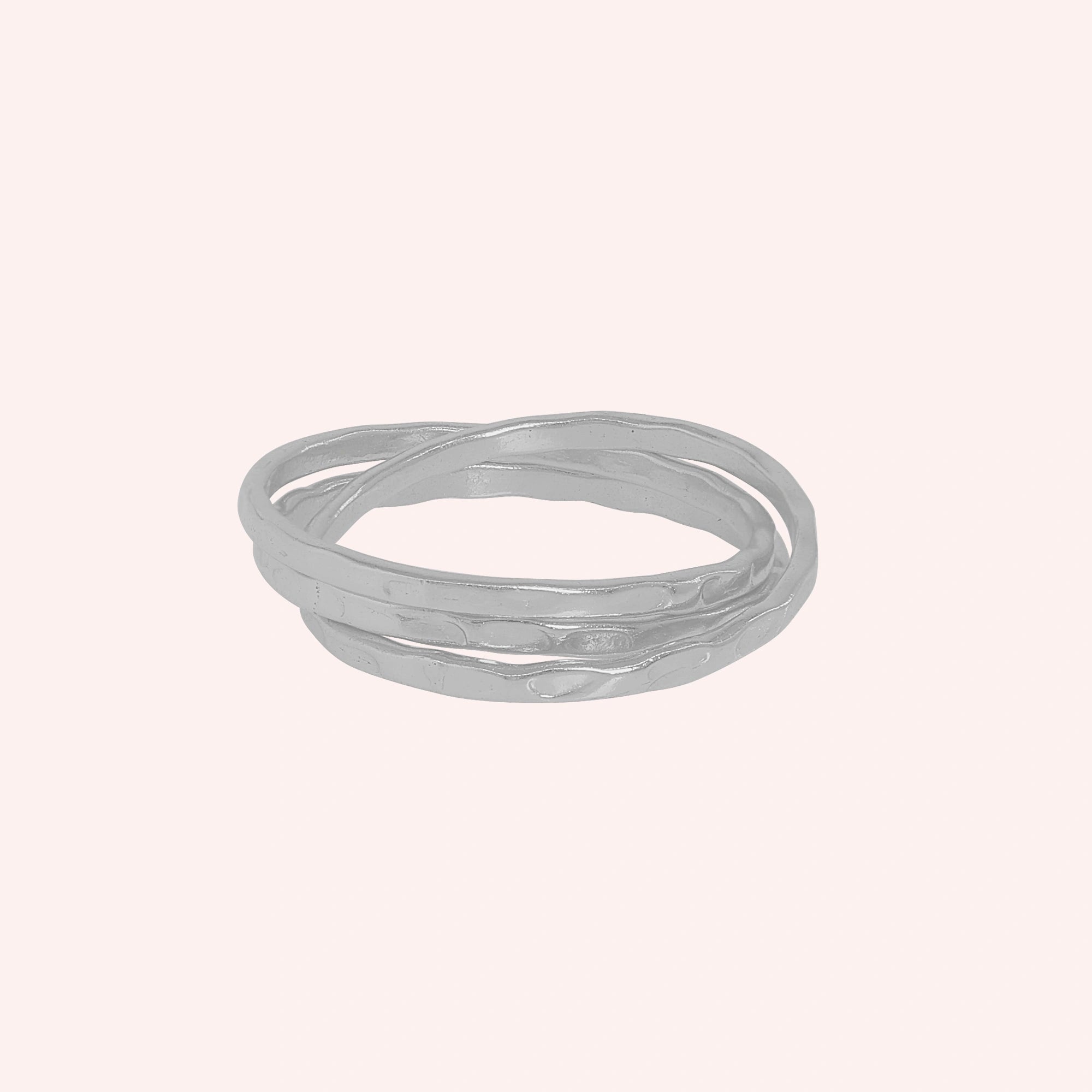 Ring_set_of_three_sterling_silver_textured_stacking_bands_at_front_angle_on_solid_pink_background