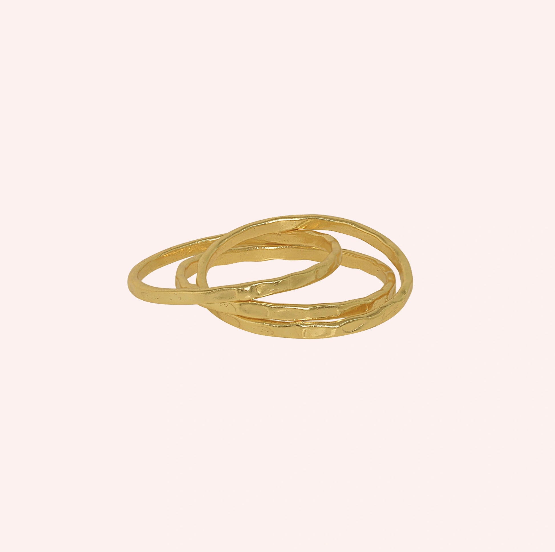 Ring_set_of_three_gold_plated_silver_textured_stacking_bands_at_front_angle_on_solid_pink_background