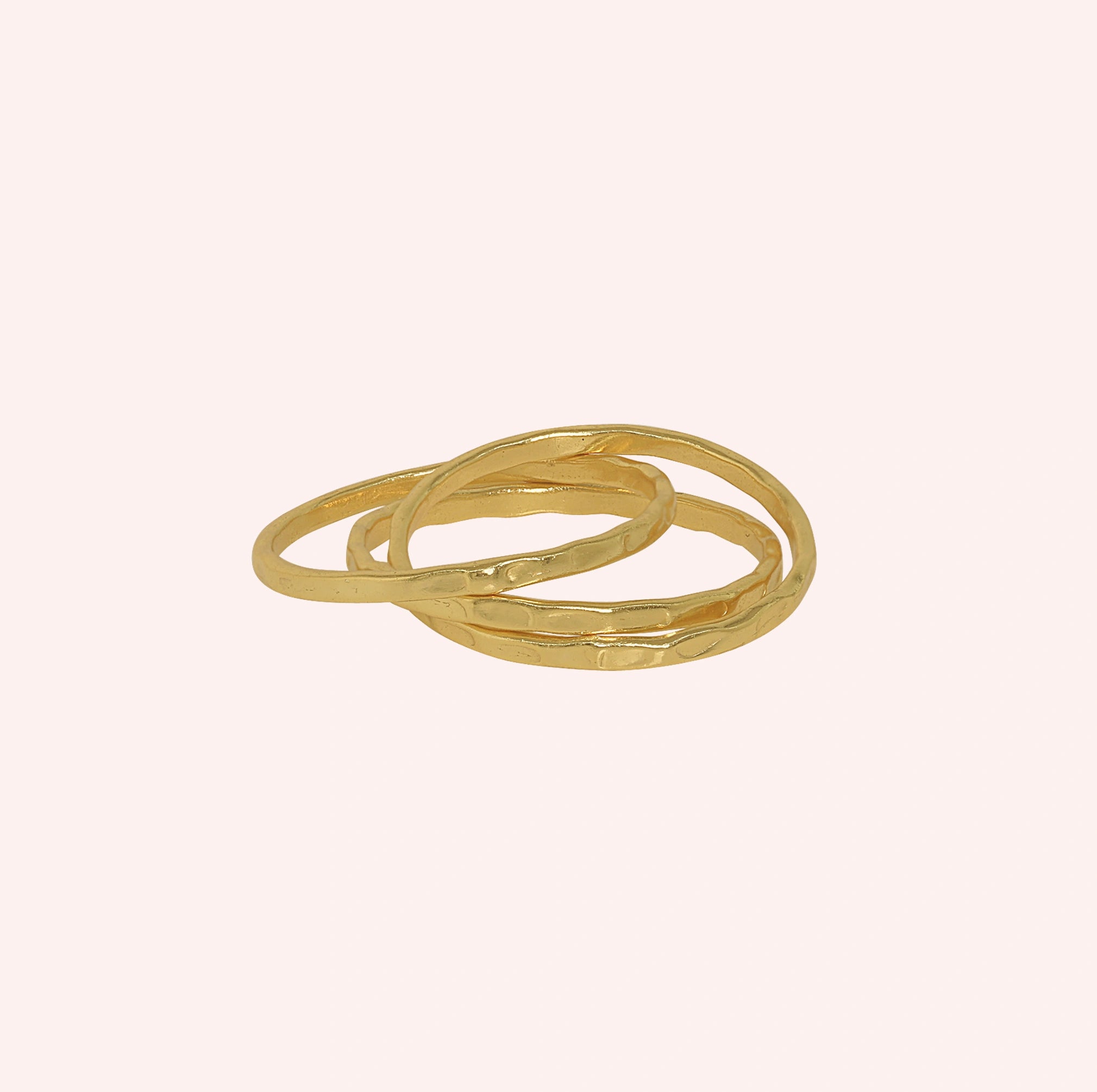 Ring_set_of_three_gold_plated_silver_textured_stacking_bands_at_front_angle_on_solid_pink_background