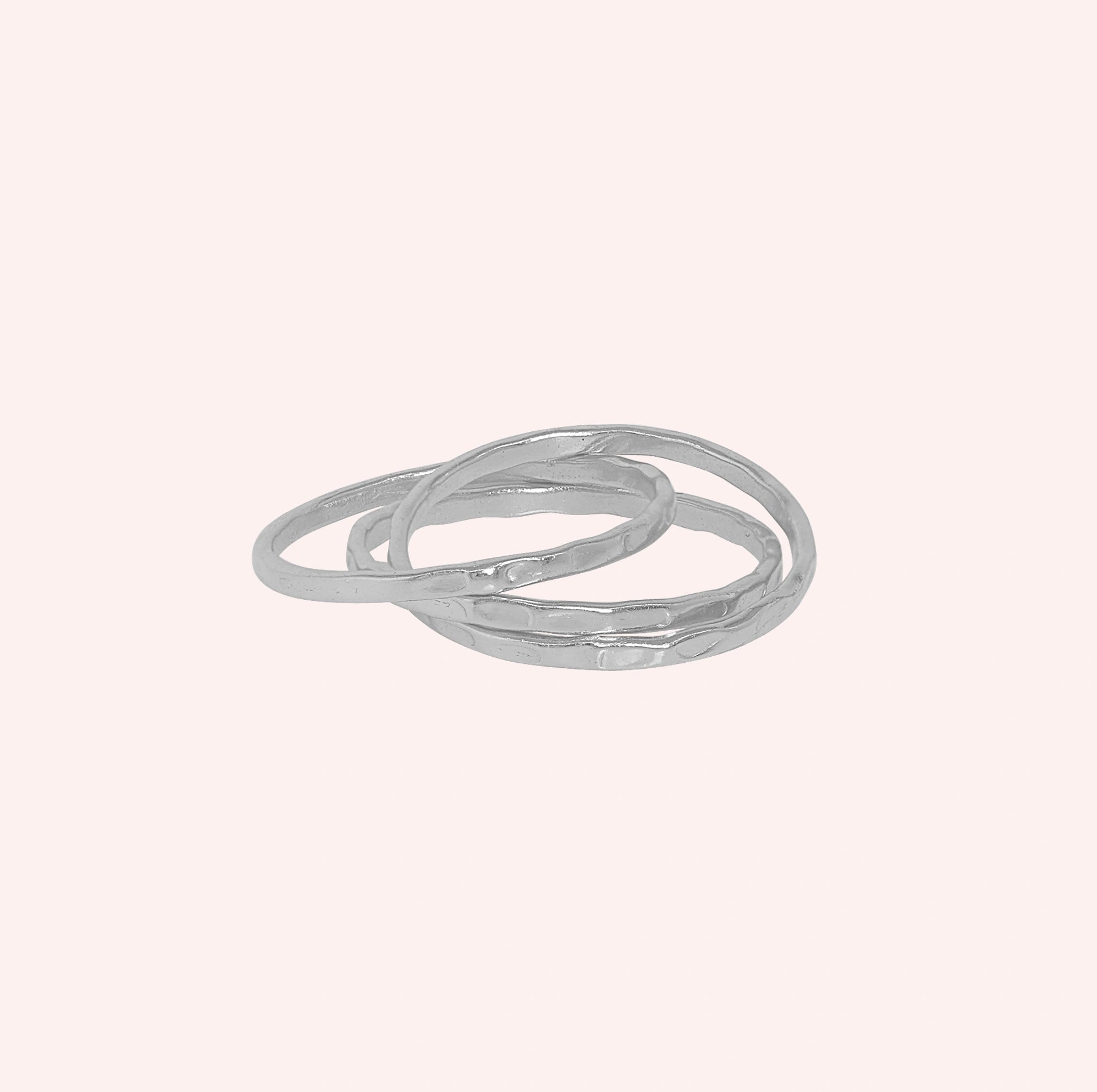 Ring_set_of_three_sterling_silver_textured_stacking_bands_at_front_angle_on_solid_pink_background