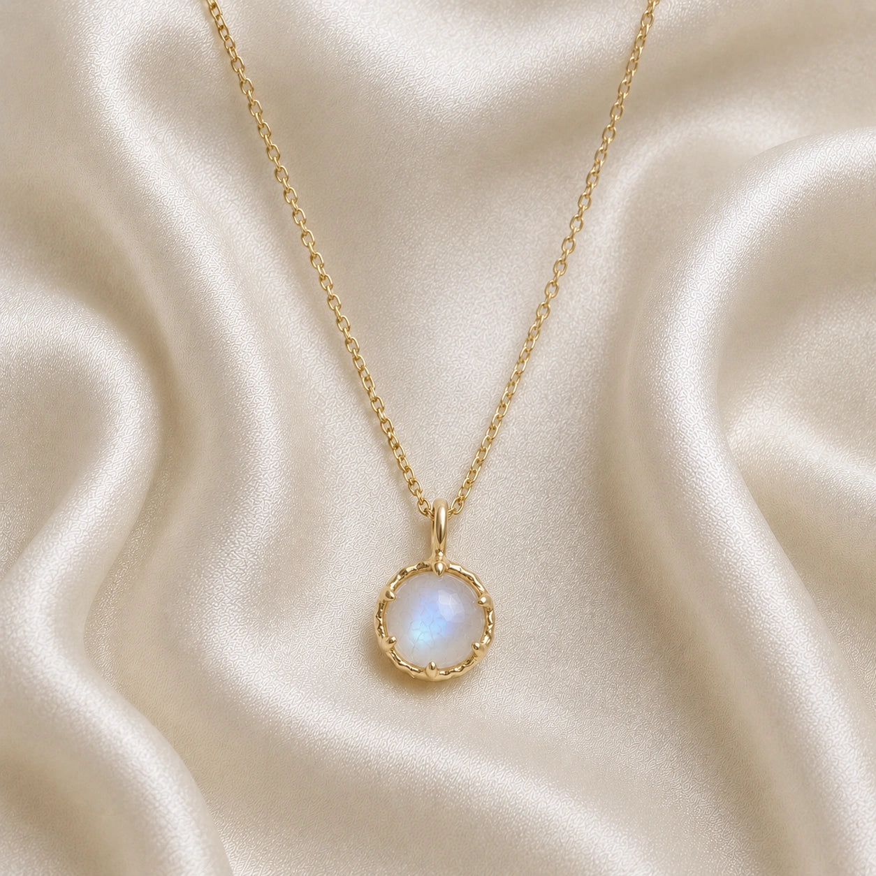 Round_necklace_in_gold_plated_silver_at_front_angle_featuring_round_moonstone_on_a_soft_fabric_background