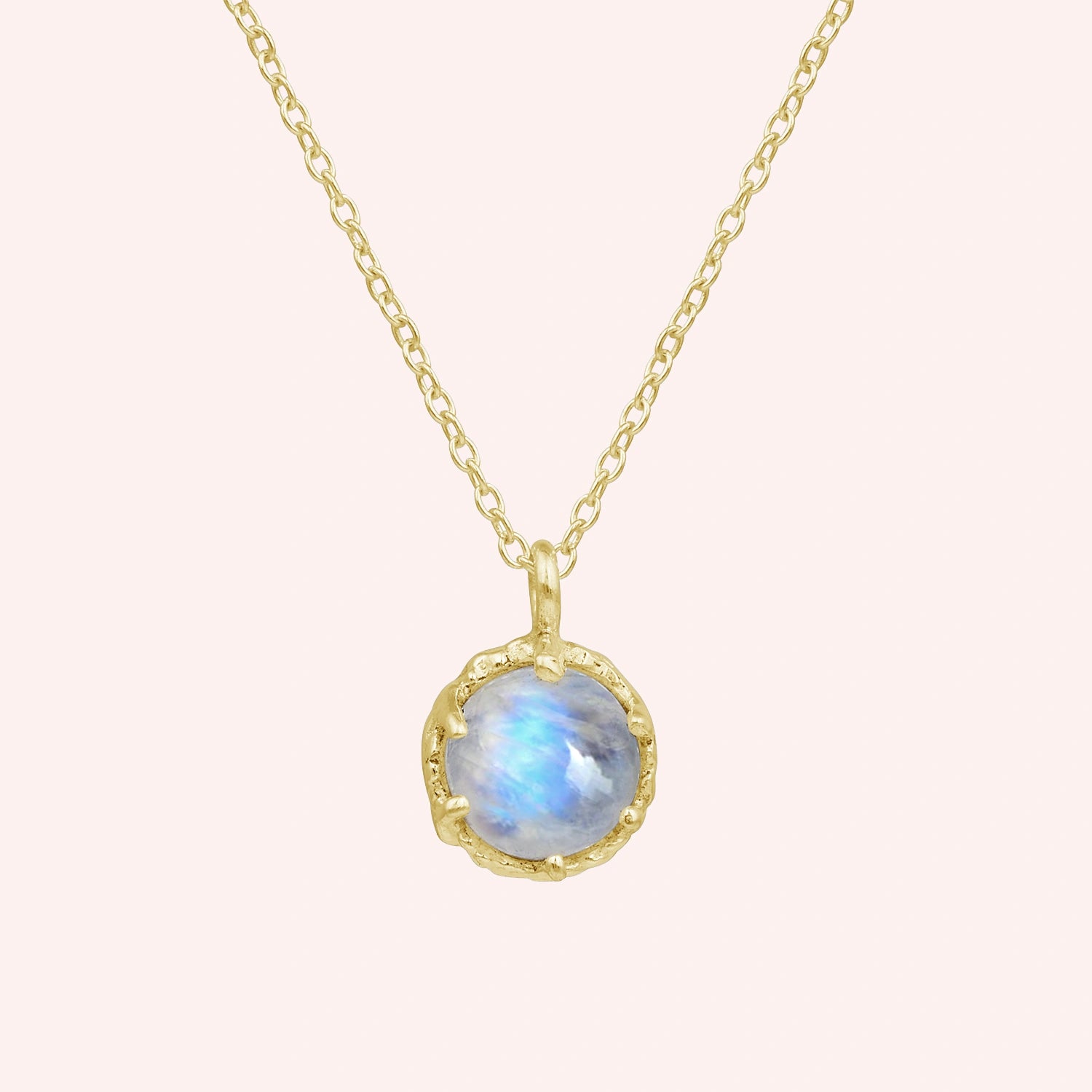 Round_necklace_in_gold_plated_silver_at_front_angle_featuring_round_moonstone_on_a_solid_pink_background