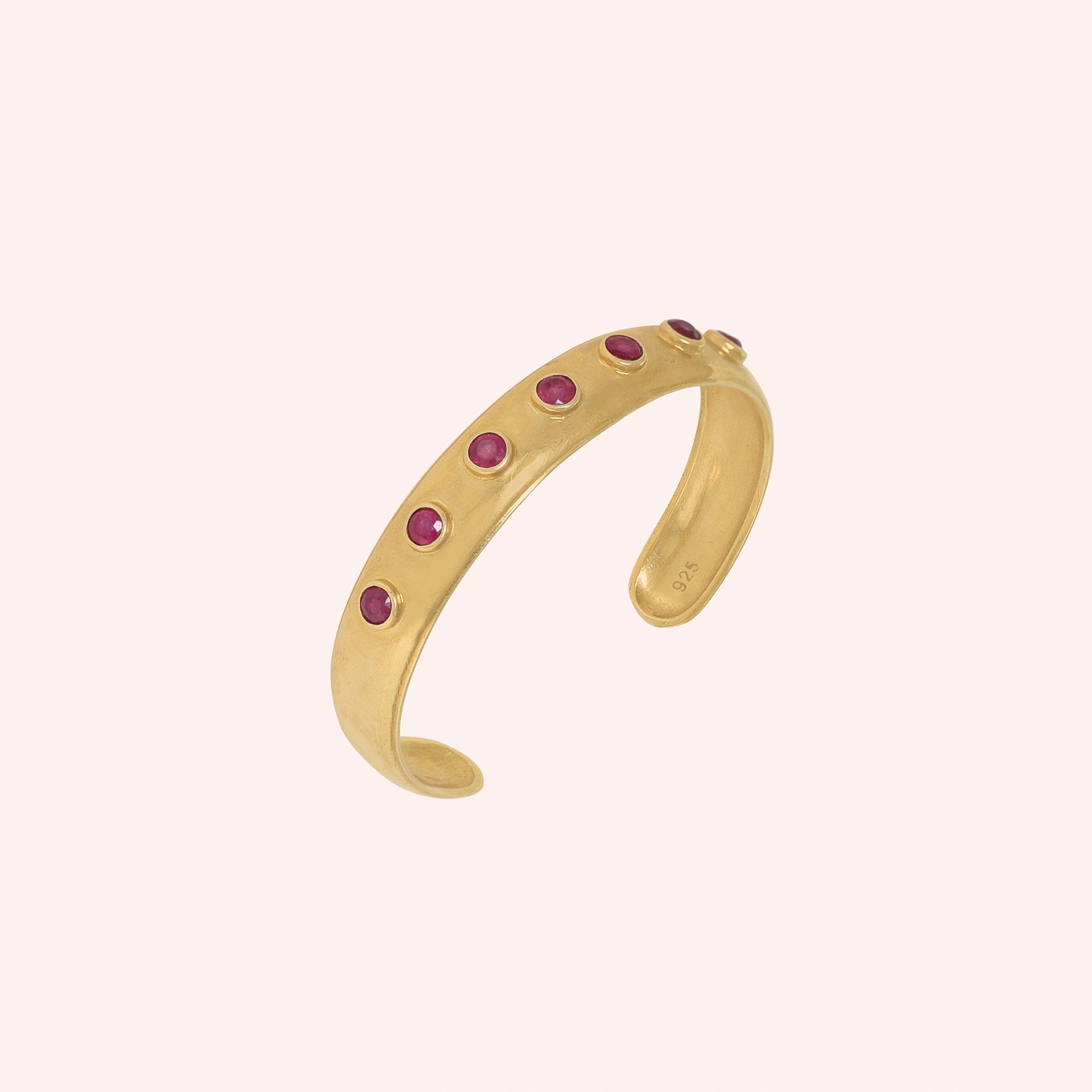 Ruby_bracelet_in_gold_plated_silver_with_round_ruby_stones_at_slight_angle_view_on_solid_pink_background