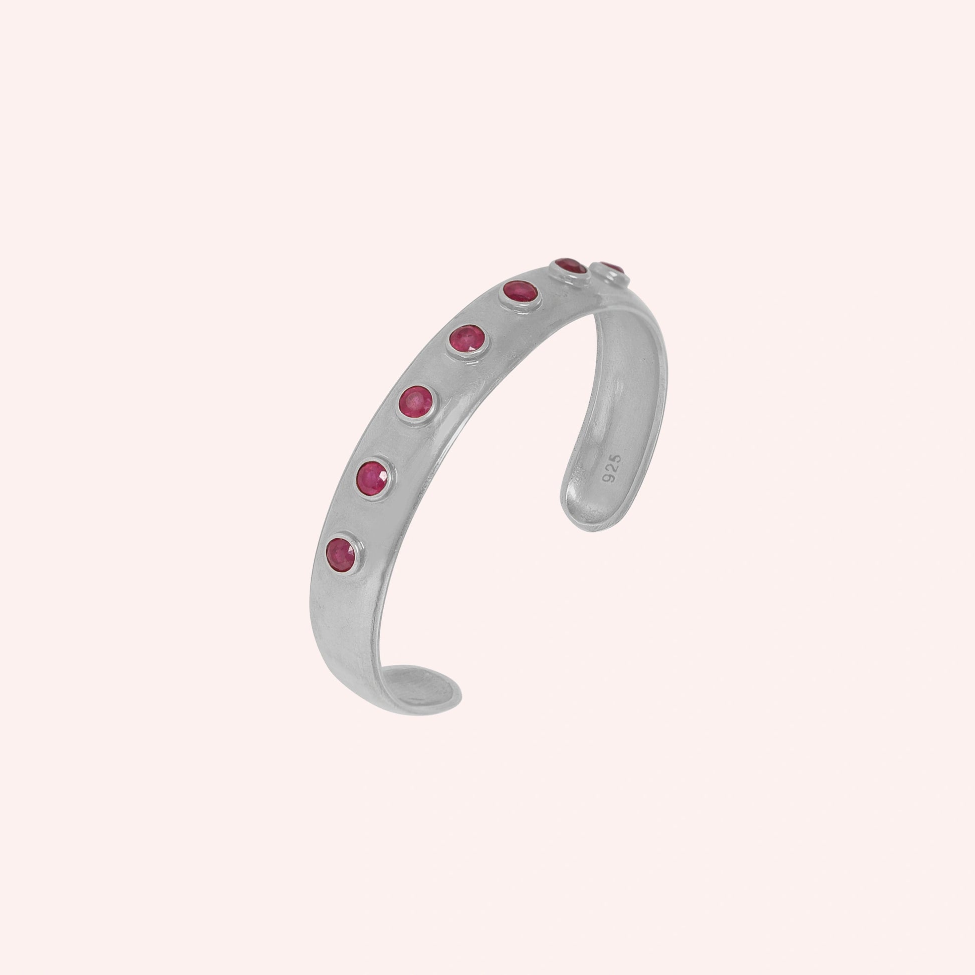 Ruby_bracelet_in_gold_plated_silver_with_round_ruby_stones_at_slight_angle_view_on_solid_pink_background