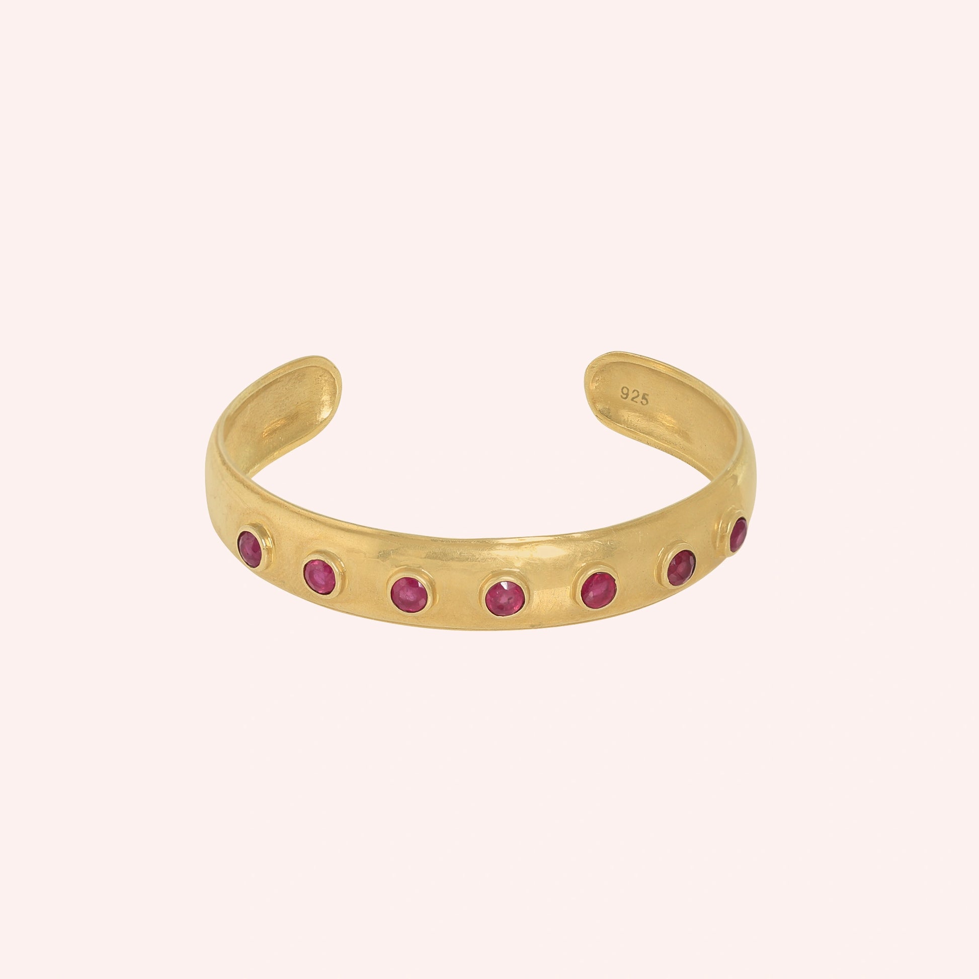 Ruby_bracelet_in_gold_plated_silver_with_round_ruby_stones_at_front_angle_view_on_solid_pink_background