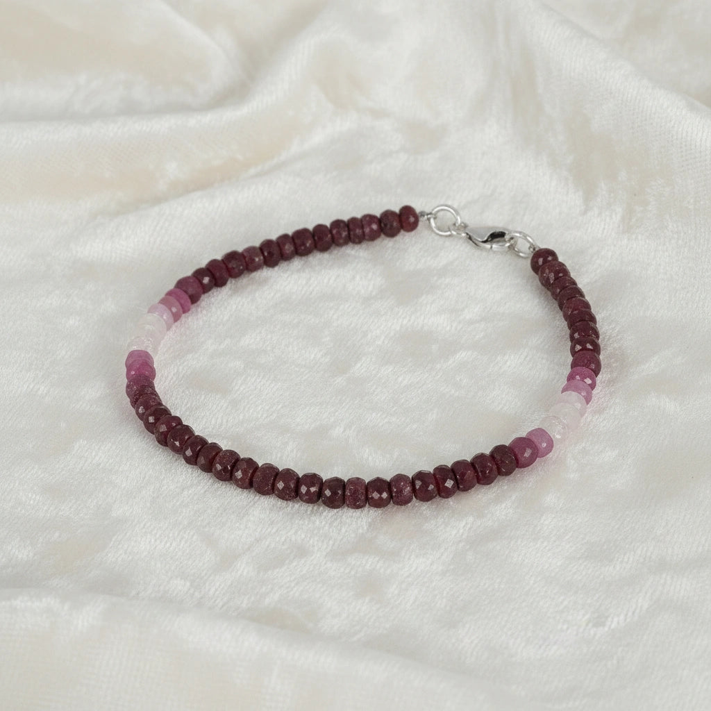 Ruby_bracelet_in_ombre_effect_with_ruby_stones_in_gradient_design_in_slight_angle_on_a_white_fabric_background