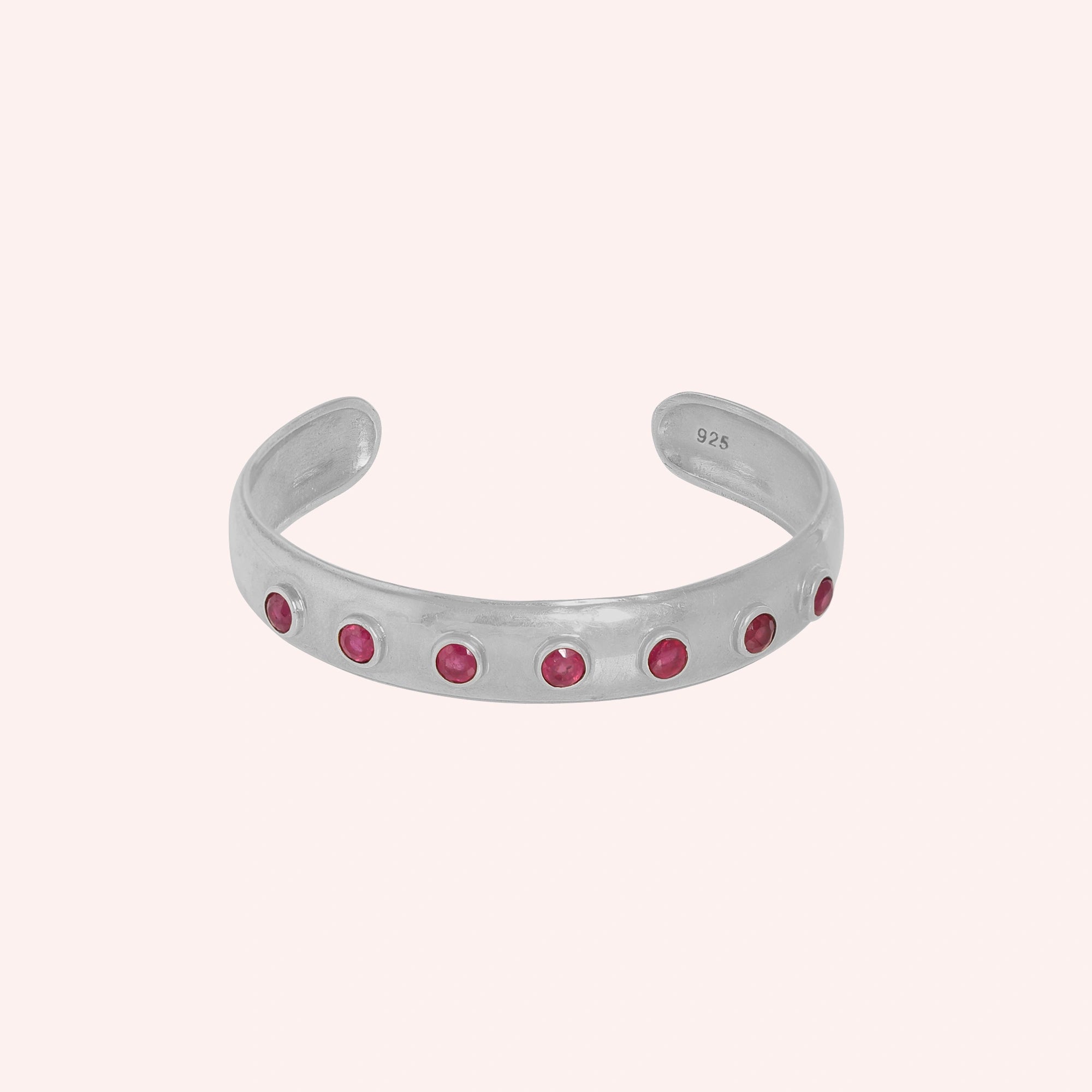 Ruby_bracelet_in_sterling_silver_with_round_ruby_stones_at_front_angle_view_on_solid_pink_background