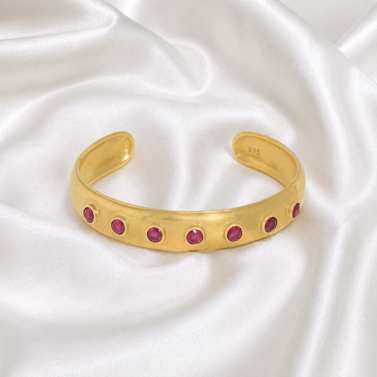 Ruby_bracelet_in_gold_plated_silver_with_round_ruby_stones_at_front_angle_view_on_soft_fabric_background