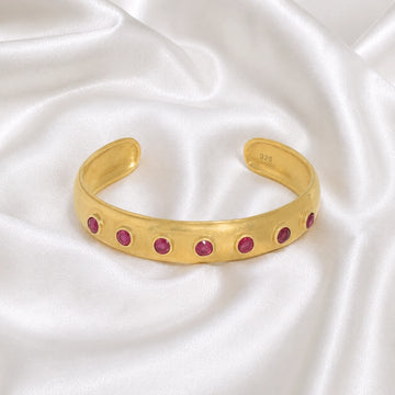 Ruby_bracelet_in_gold_plated_silver_with_round_ruby_stones_at_front_angle_view_on_soft_fabric_background