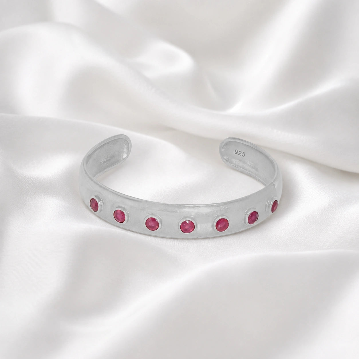 Ruby_bracelet_in_sterling_silver_with_round_ruby_stones_at_front_angle_view_on_soft_fabric_background