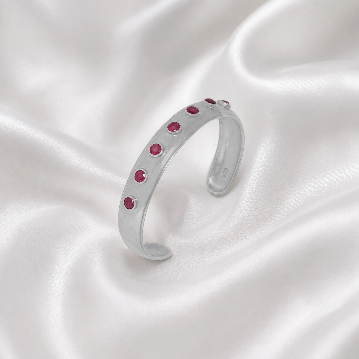 Ruby_bracelet_in_sterling_silver_with_round_ruby_stones_at_slight_angle_view_on_soft_fabric_background