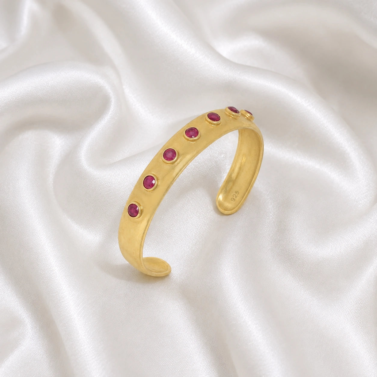 Ruby_bracelet_in_gold_plated_silver_with_round_ruby_stones_at_slight_angle_view_on_soft_fabric_background