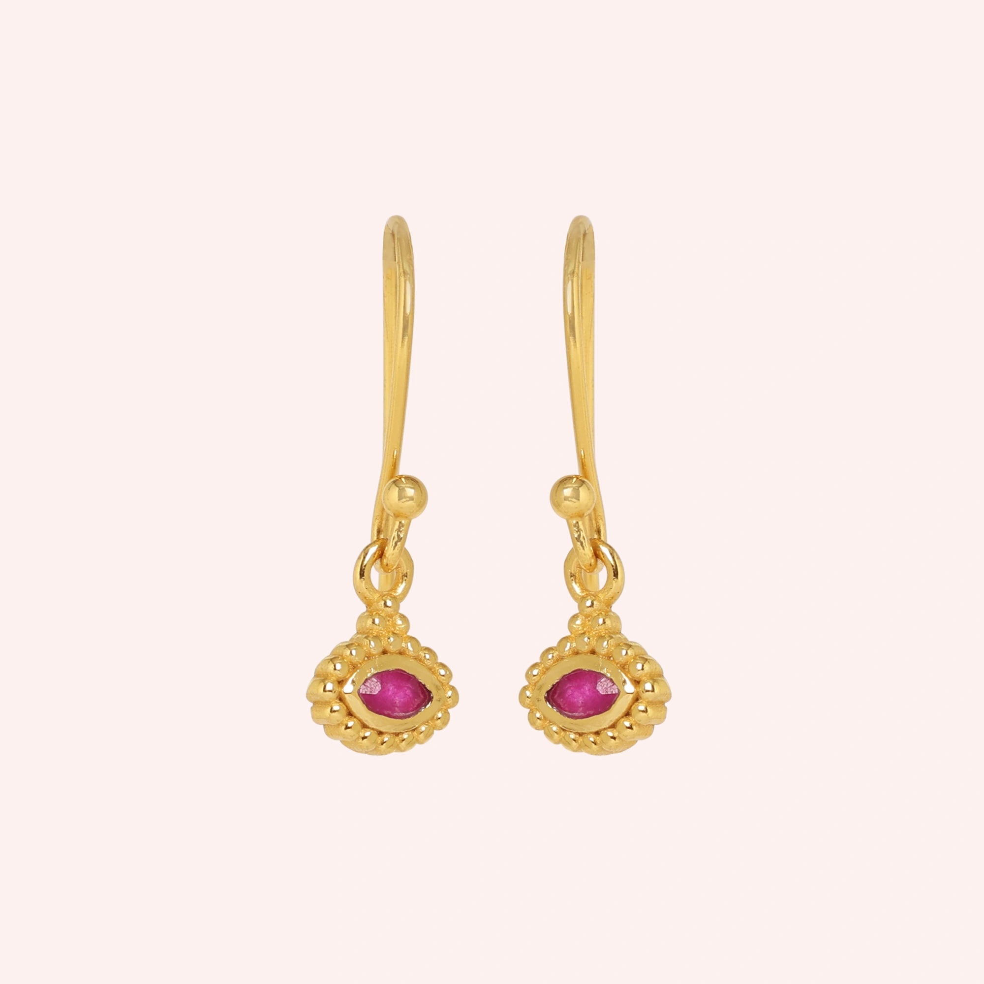 Ruby_earrings_in_gold_plated_silver_with_marquise_ruby_stone_at_front_angle_view_on_solid_pink_background