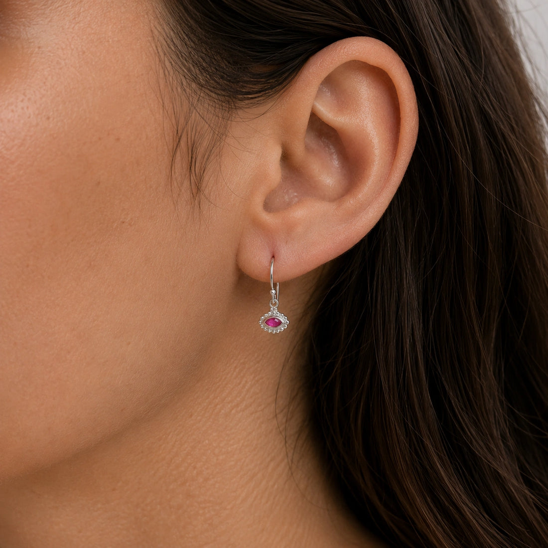 Ruby_earrings_in_gold_plated_silver_with_marquise_ruby_stone_at_front_angle_view_on_soft_fabric_background