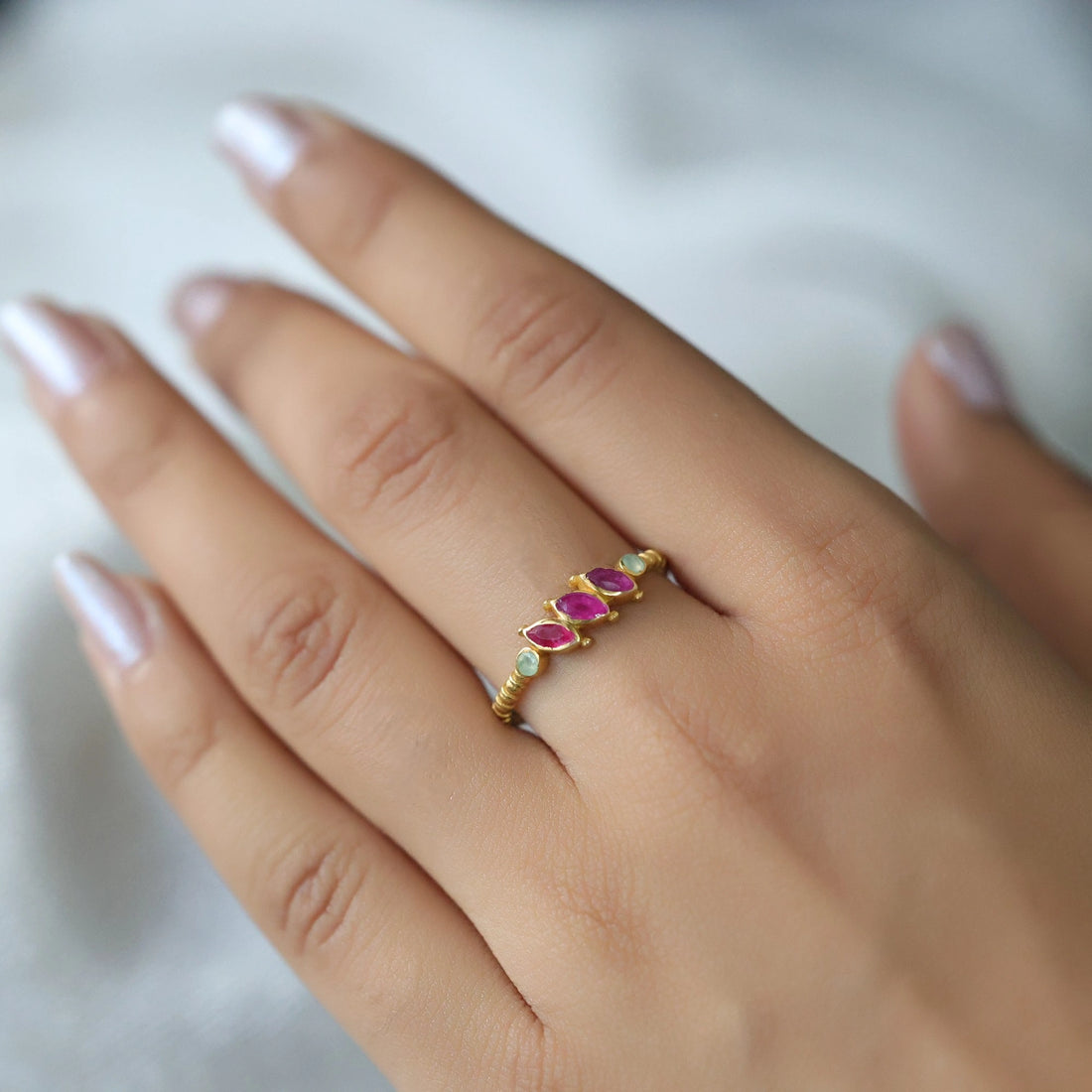 Ruby-ring-with-pink-and-green-gemstones-gold-plated-silver-angled-view-on-white-satin-background