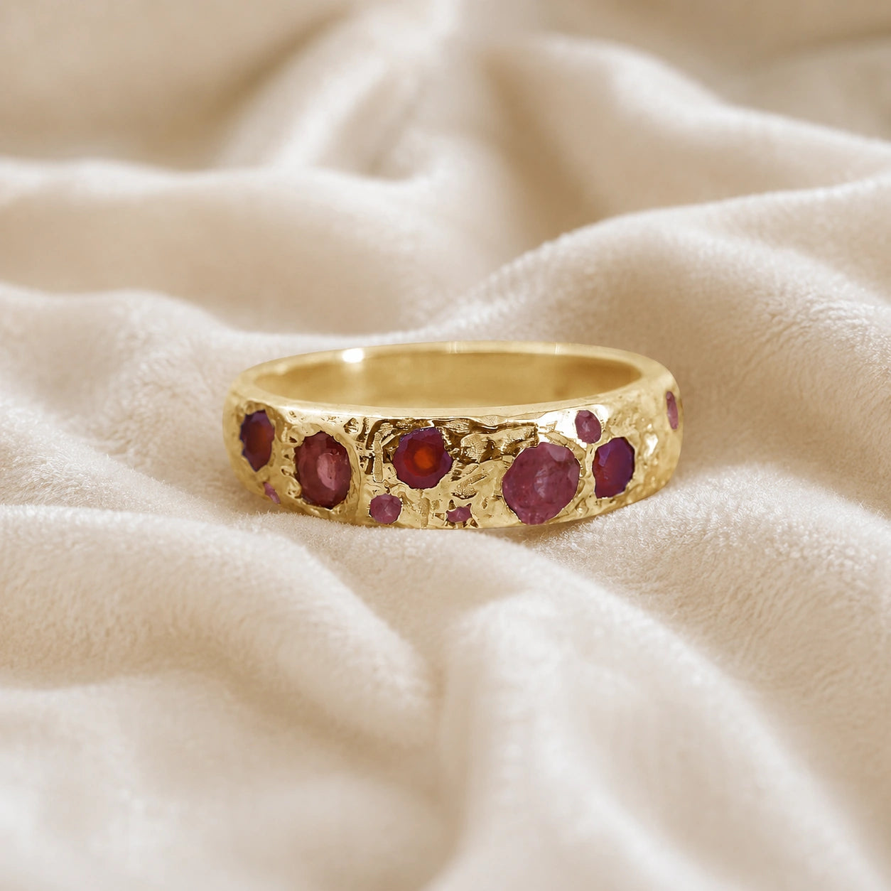Ruby_stone_ring_in_gold_plated_silver_with_multiple_ruby_stones_at_front_angle_on_soft_fabric_background