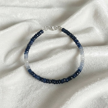 Sapphire_bracelet_in_ombre_effect_with_sapphire_stones_in_gradient_design_in_front_angle_on_a_white_fabric_background