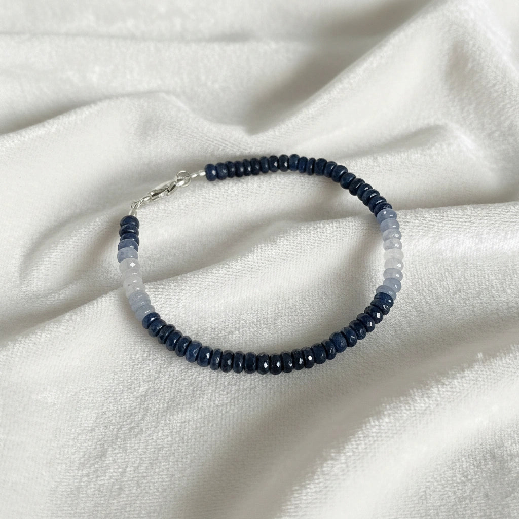 Sapphire_bracelet_in_ombre_effect_with_sapphire_stones_in_gradient_design_in_slight_angle_on_a_white_fabric_background