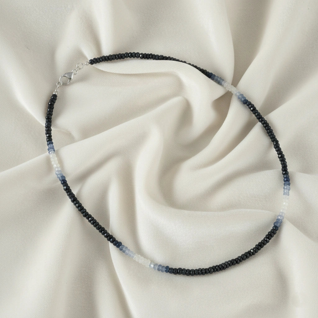 Sapphire_necklace_in_ombre_effect_with_sapphire_stones_in_gradient_design_in_slight_angle_on_a_white_fabric_background