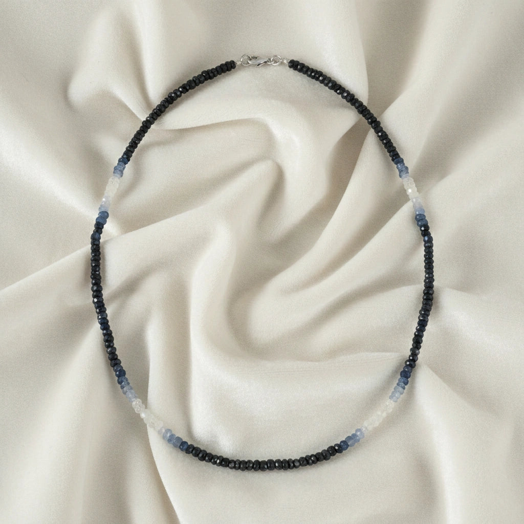 Sapphire_necklace_in_ombre_effect_with_sapphire_stones_in_gradient_design_in_front_angle_on_a_white_fabric_background