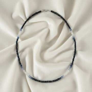 Sapphire_necklace_in_ombre_effect_with_sapphire_stones_in_gradient_design_in_front_angle_on_a_white_fabric_background