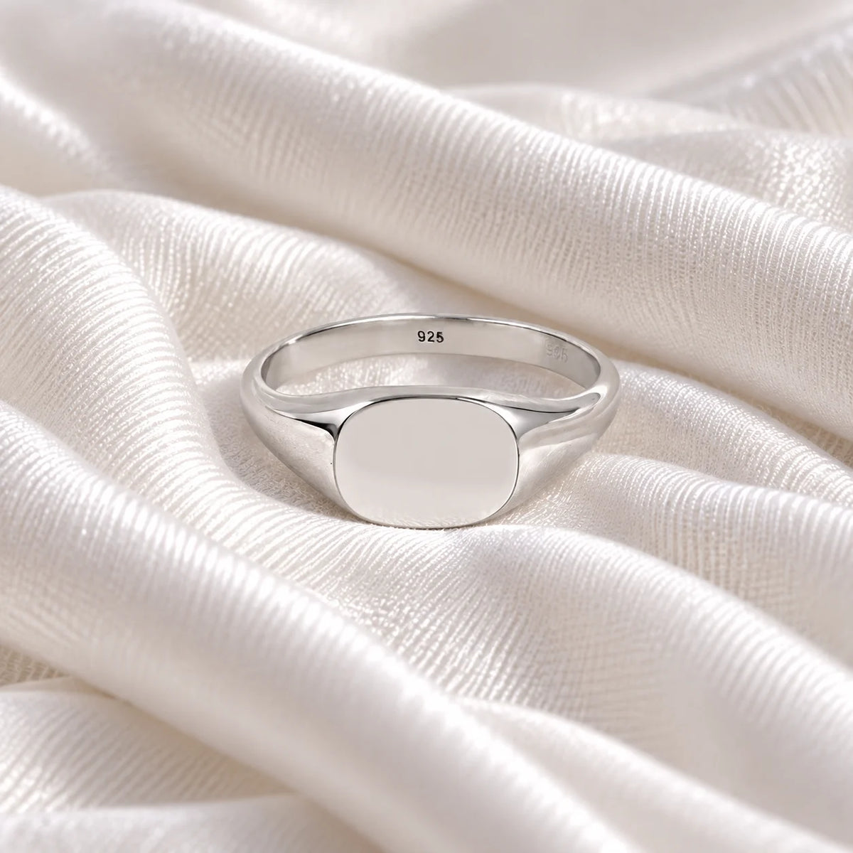 Signet_ring_in_sterling_silver_with_at_front_angle_view_on_soft_fabric_background