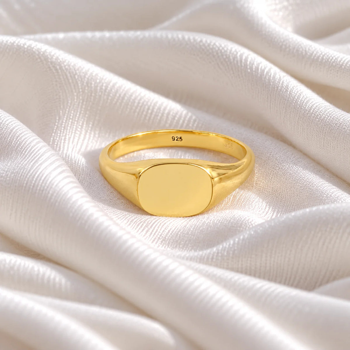 Signet_ring_in_gold_plated_silver_with_at_front_angle_view_on_soft_fabric_background