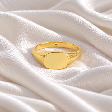 Signet_ring_in_gold_plated_silver_with_at_front_angle_view_on_soft_fabric_background