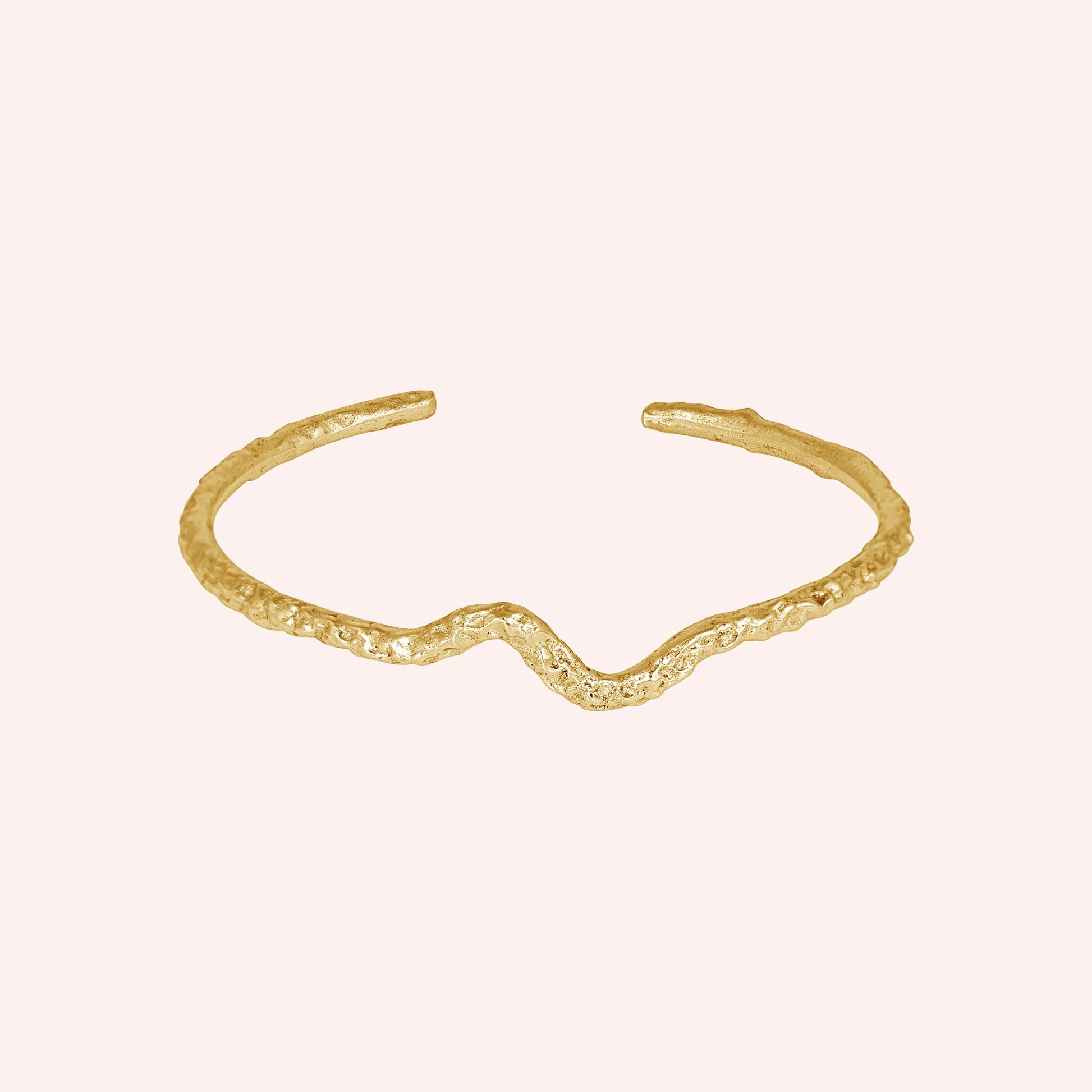 Silver cuff bracelet shown at front angled view featuring gold plated textured open cuff design displayed on a pink background