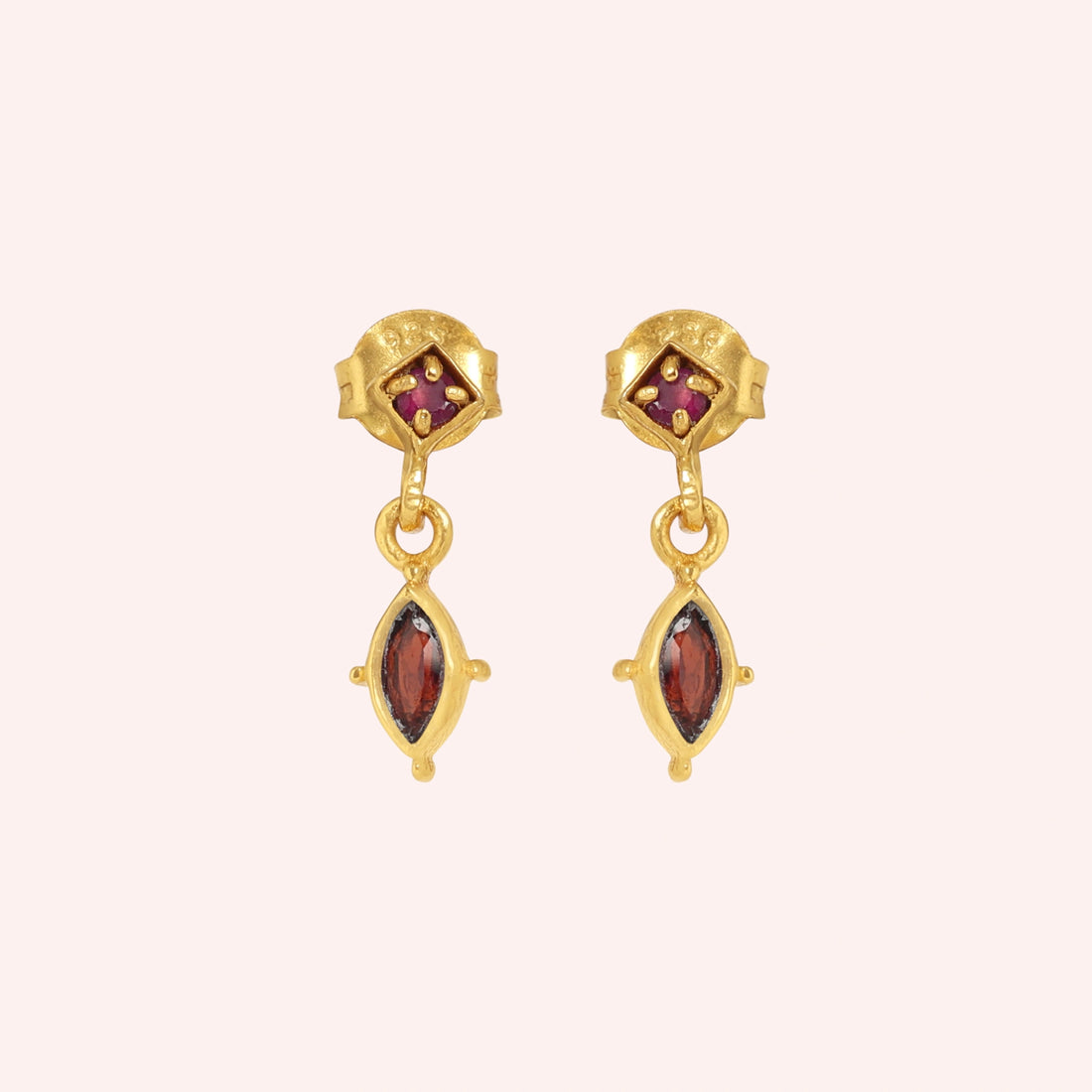 Silver_drop_earrings_in_gold_plated_silver_with_ruby_and_garnet_stones_at_front_angle_view_on_solid_pink_background