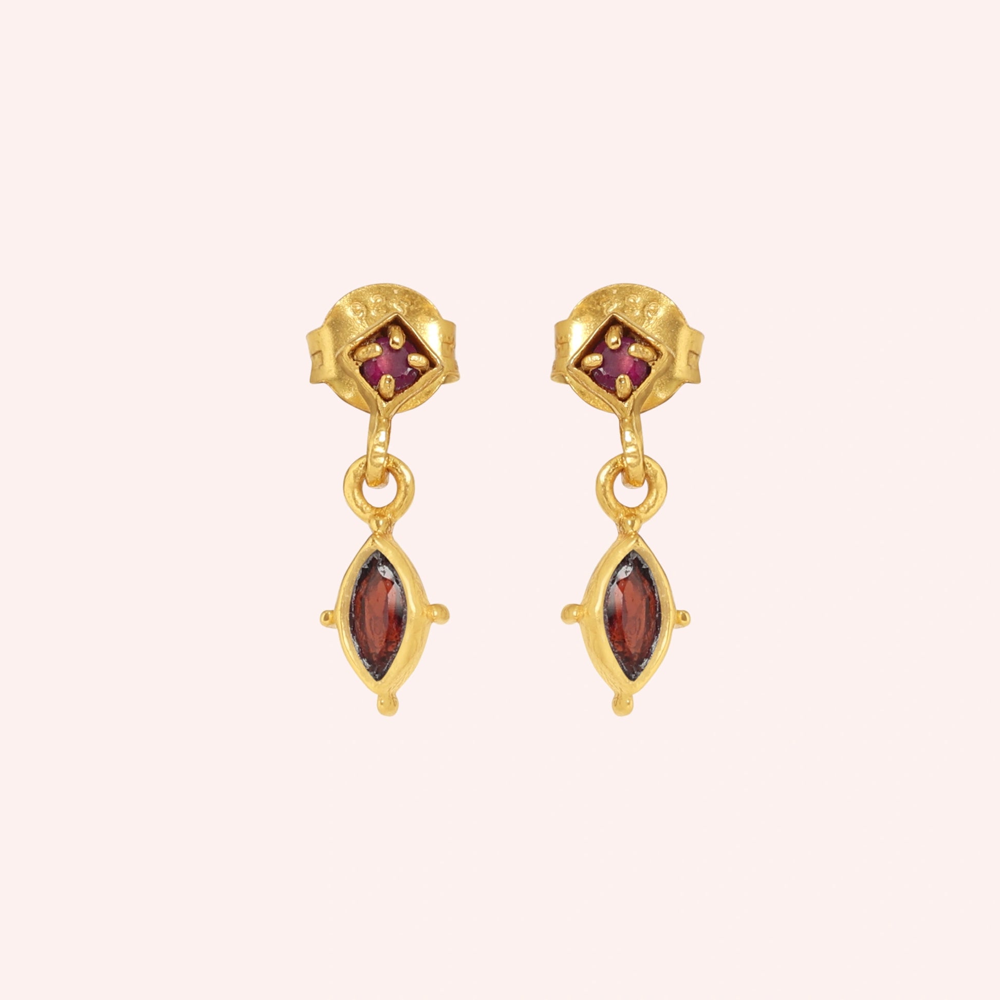 Silver_drop_earrings_in_gold_plated_silver_with_ruby_and_garnet_stones_at_front_angle_view_on_solid_pink_background