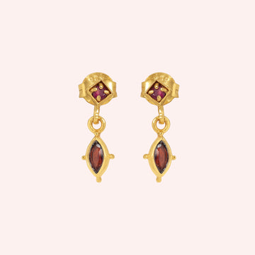 Silver_drop_earrings_in_gold_plated_silver_with_ruby_and_garnet_stones_at_front_angle_view_on_solid_pink_background