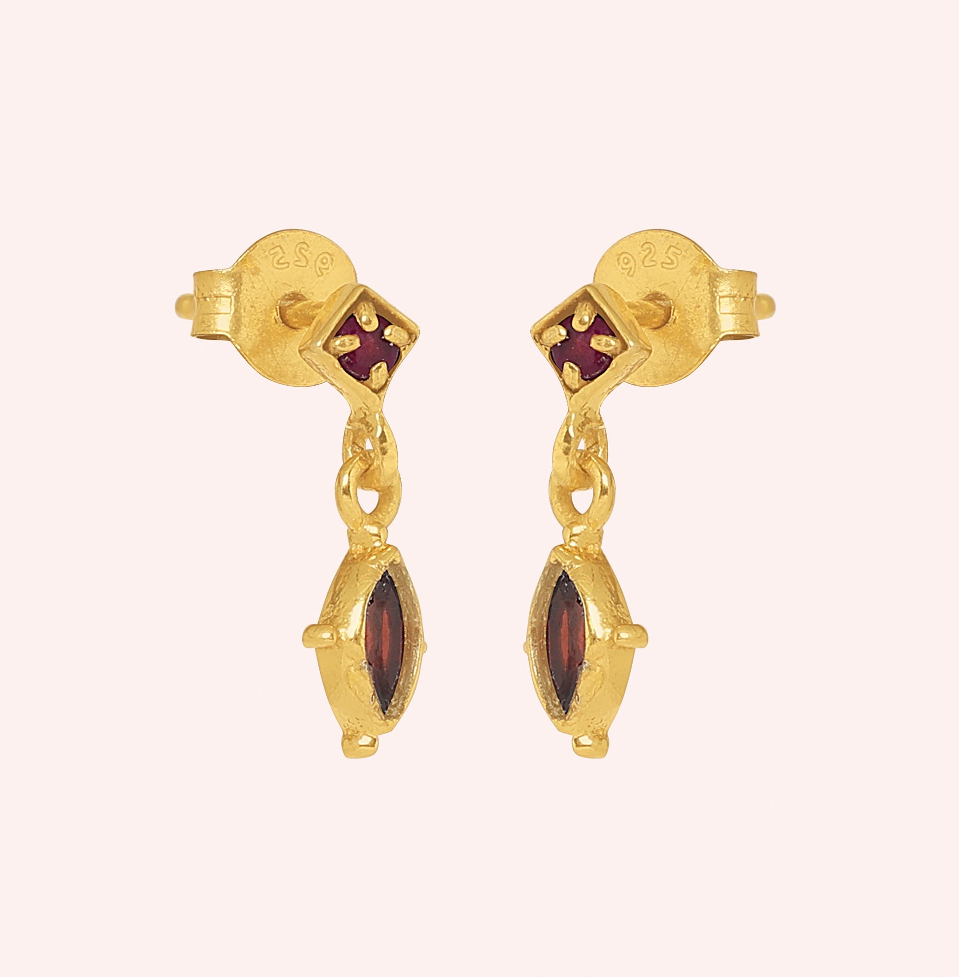 Silver_drop_earrings_in_gold_plated_silver_with_ruby_and_garnet_stones_at_slight_angle_view_on_solid_pink_background