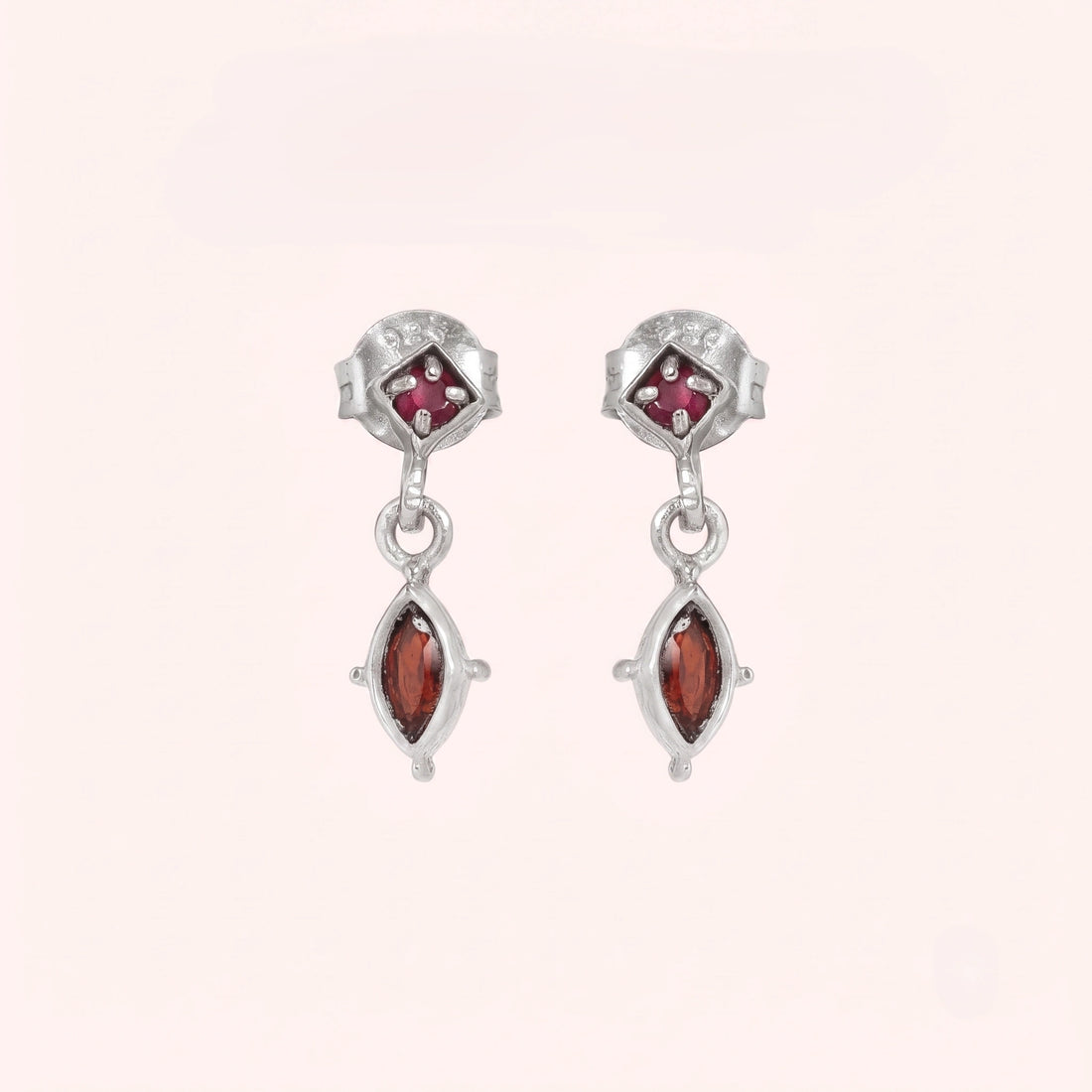 Silver_drop_earrings_in_gold_plated_silver_with_ruby_and_garnet_stones_at_front_angle_view_on_solid_pink_background