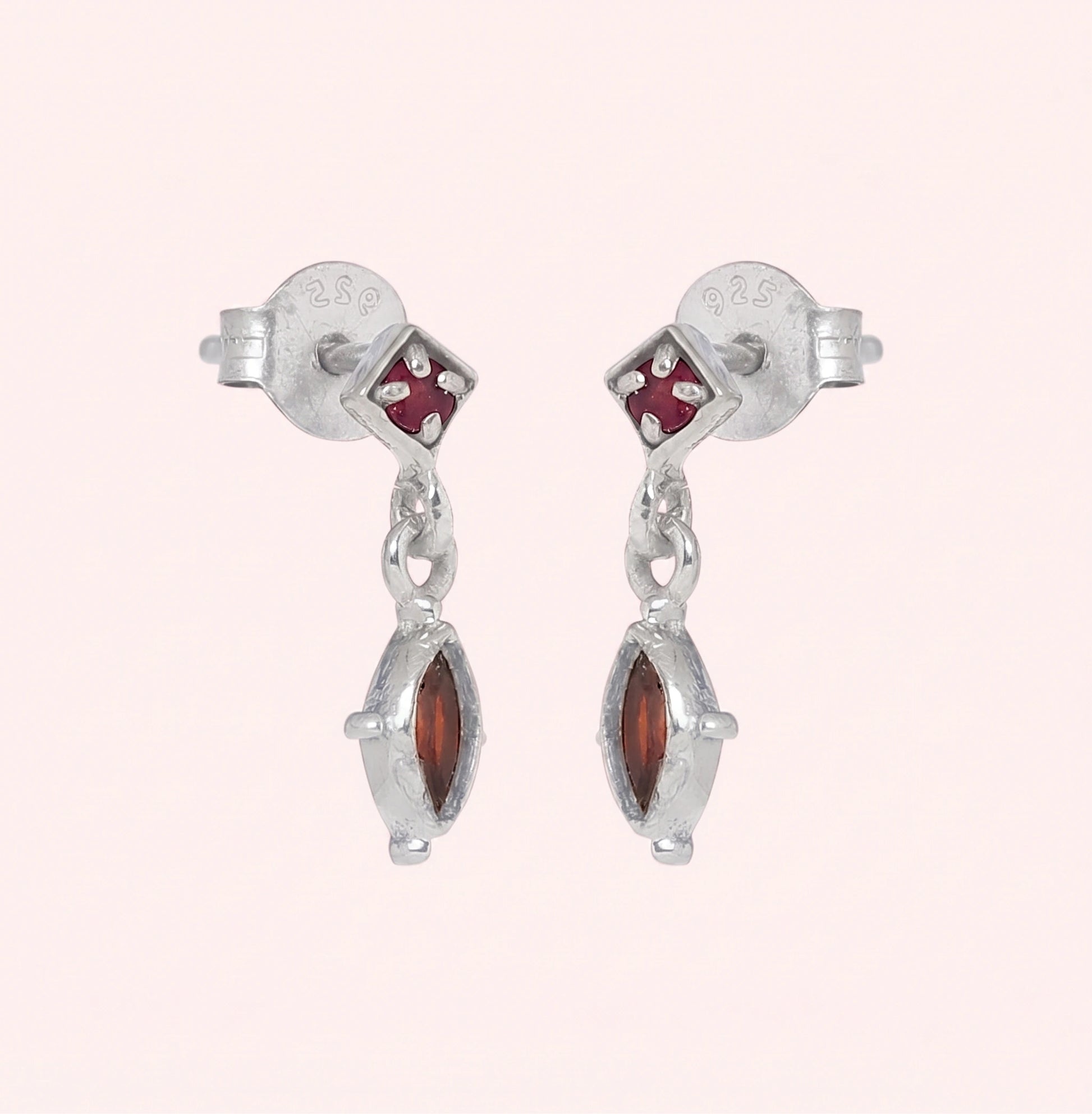 Silver_drop_earrings_in_sterling_silver_with_ruby_and_garnet_stones_at_slight_angle_view_on_solid_pink_background
