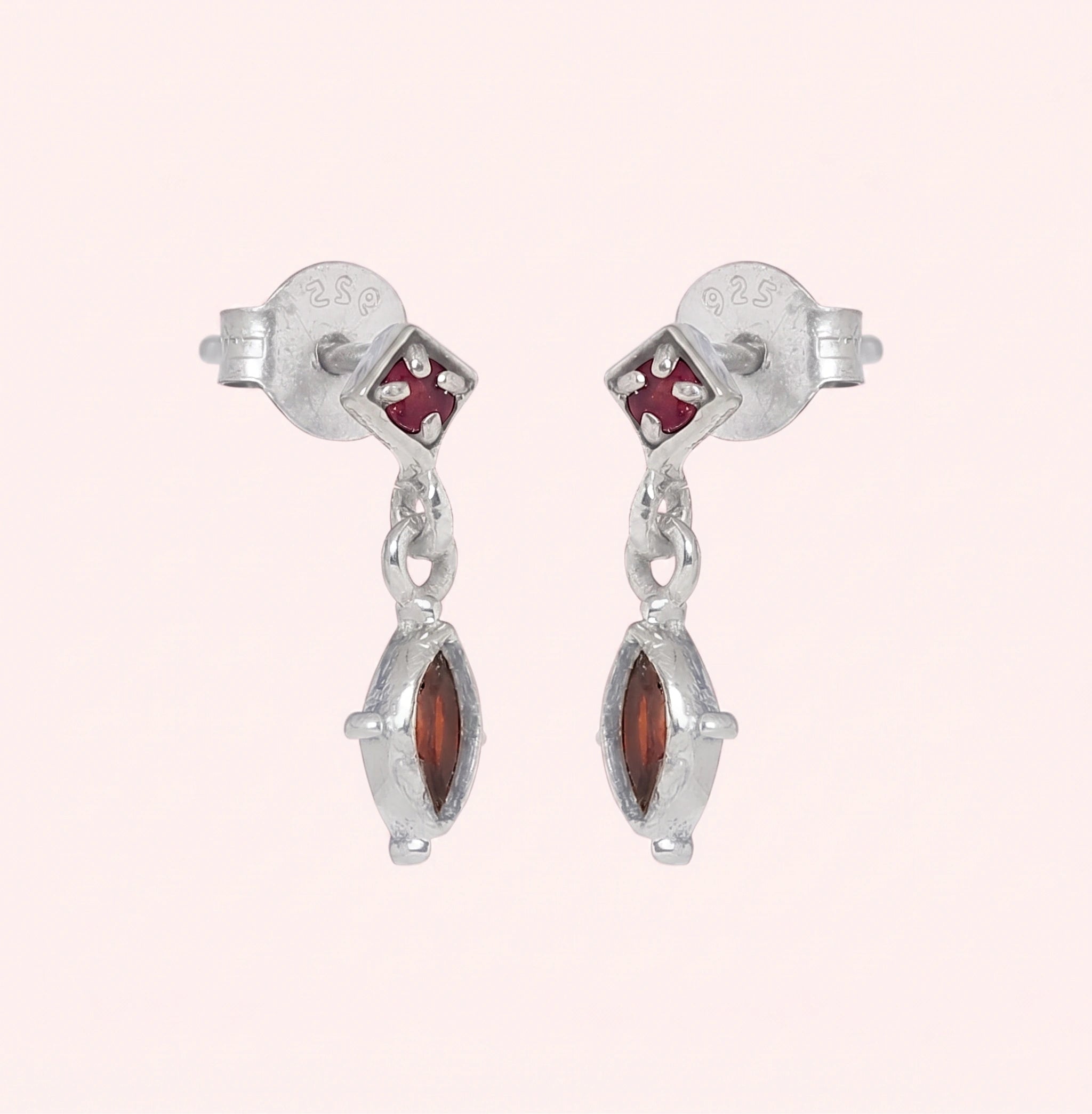 Silver_drop_earrings_in_sterling_silver_with_ruby_and_garnet_stones_at_slight_angle_view_on_solid_pink_background