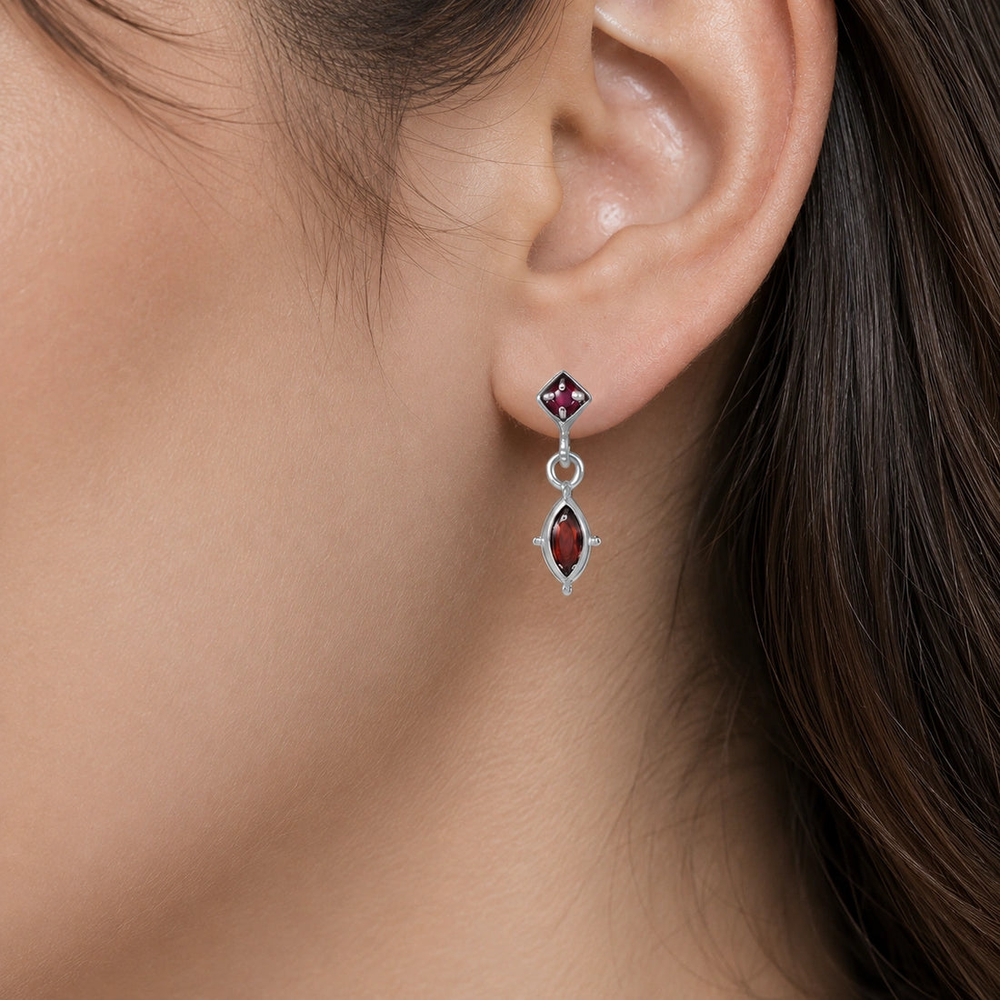 Silver_drop_earrings_in_gold_plated_silver_with_ruby_and_garnet_stones_at_front_angle_view_on_soft_fabric_background