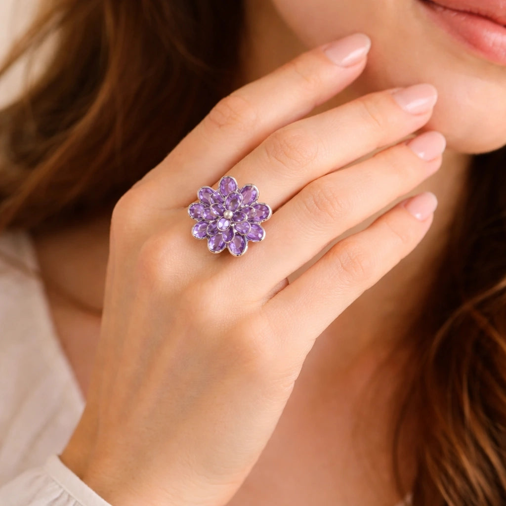 silver_flower_ring_flower_engagement_ring_with_purple_gem_petals_in_silver_setting_angled_view_on_soft_white_fabric_background