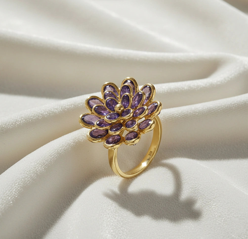 silver_flower_ring_flower_engagement_ring_with_purple_gem_petals_in_gold_plated_setting_angled_view_on_white_fabric_background