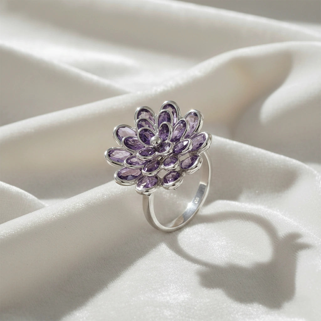 silver_flower_ring_flower_engagement_ring_with_purple_gem_petals_in_silver_setting_angled_view_on_soft_white_fabric_background