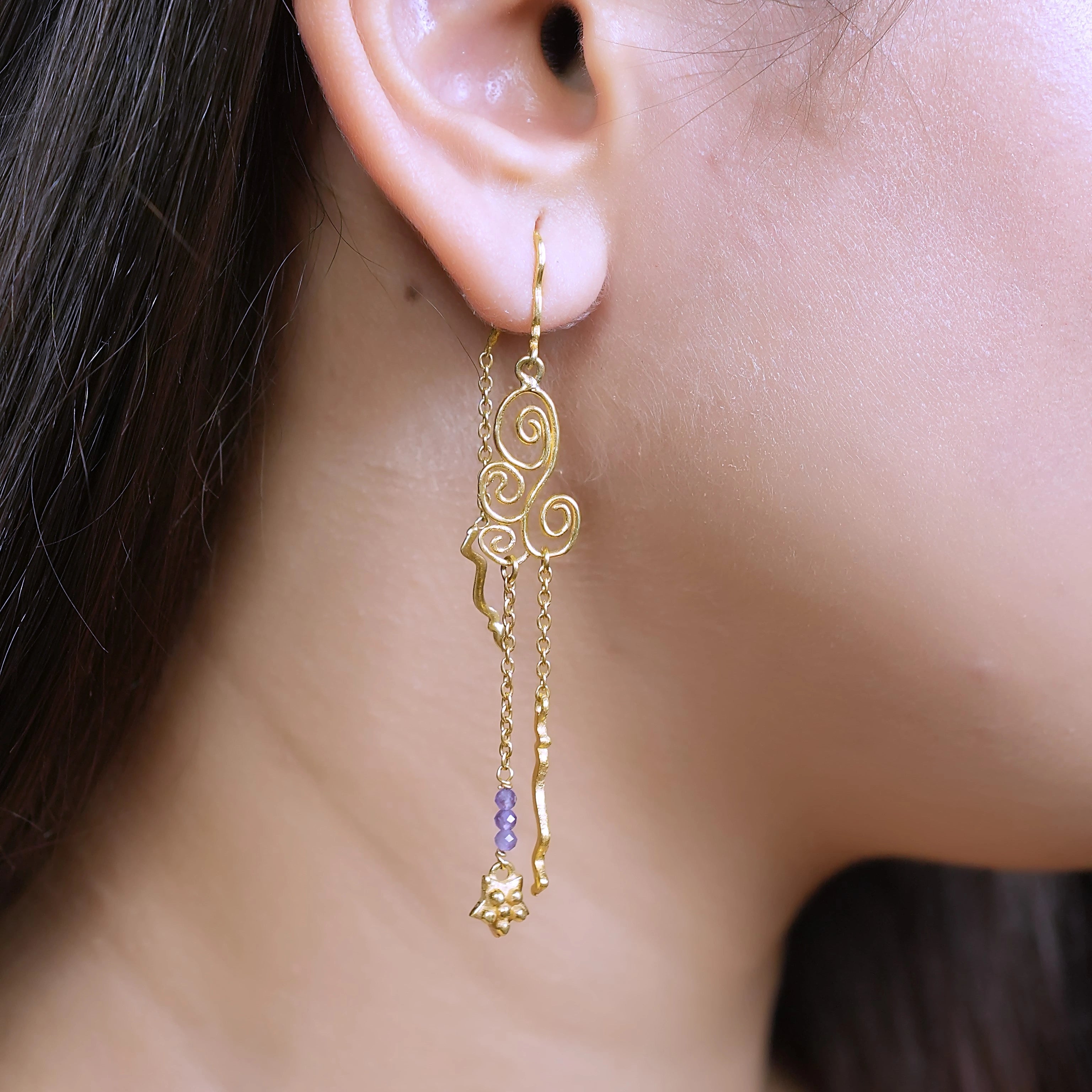 side_angle_silver_hanging_earrings_gold_plated_scroll_drop_with_purple_beads_worn_on_ear_trendy_earrings_soft_focus_background