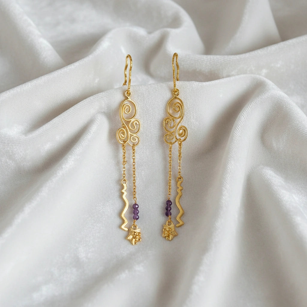 front_angle_silver_hanging_earrings_gold_plated_scroll_design_with_purple_beads_trendy_earrings_on_soft_white_fabric_cloth