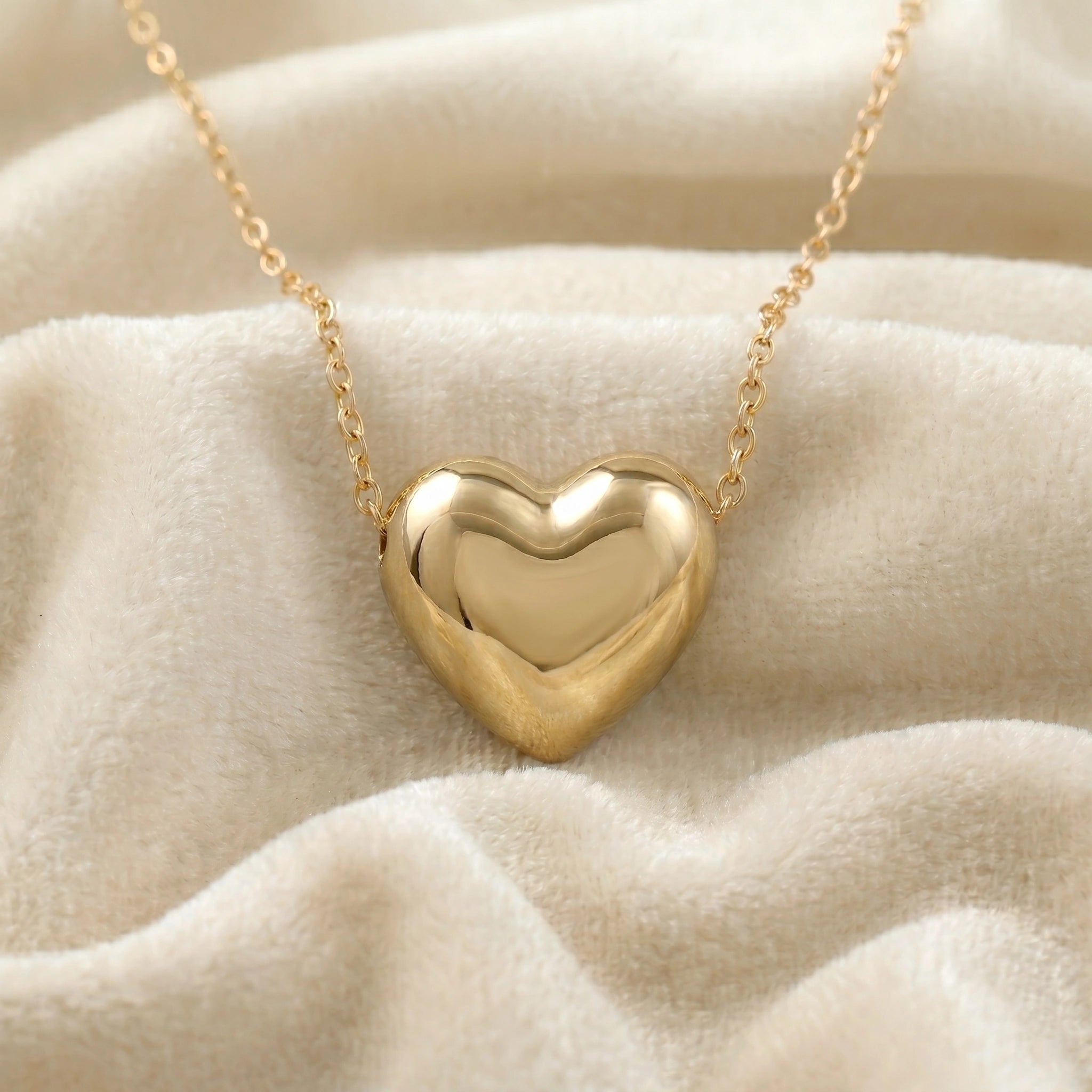 Silver_heart_necklace_shown_in_front_angled_view_with_gold_plated_silver_with_chain_on_soft_fabirc_background