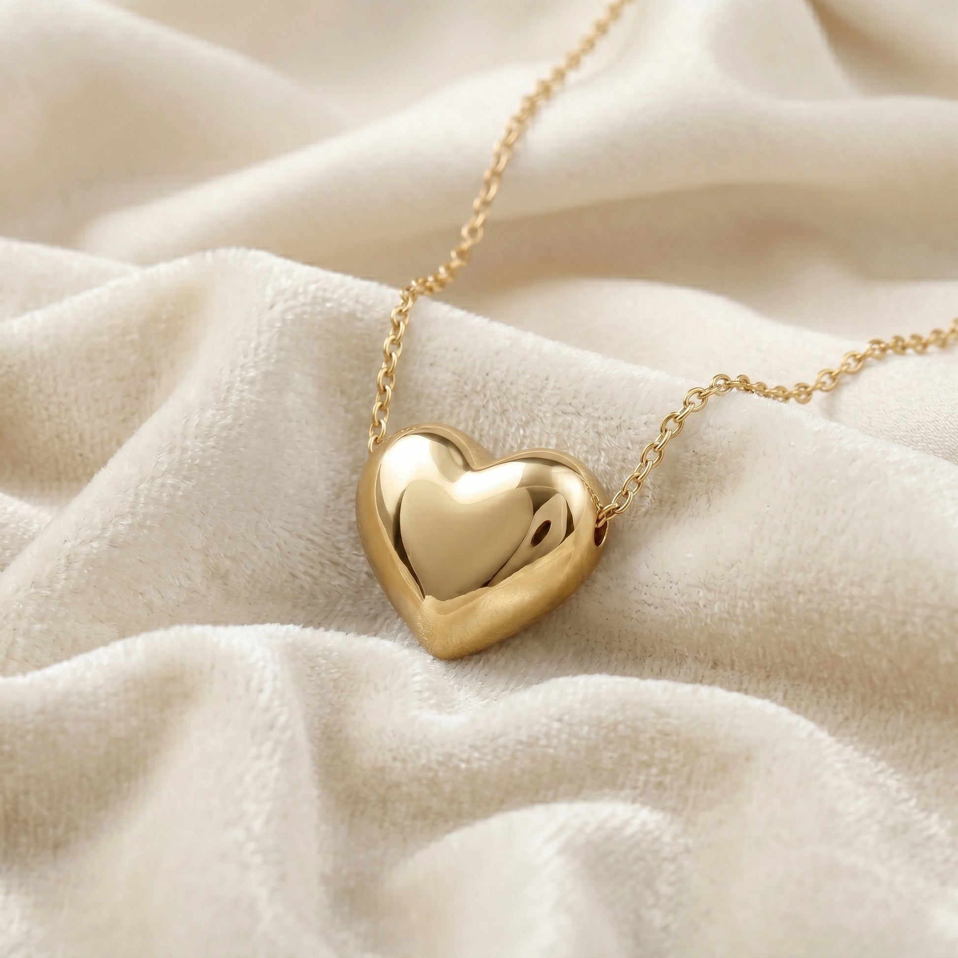 Silver_heart_necklace_shown_in_slightly_angled_view_with_gold_plated_silver_with_chain_on_soft_white_fabric_background