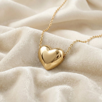 Silver_heart_necklace_shown_in_slightly_angled_view_with_gold_plated_silver_with_chain_on_soft_white_fabric_background