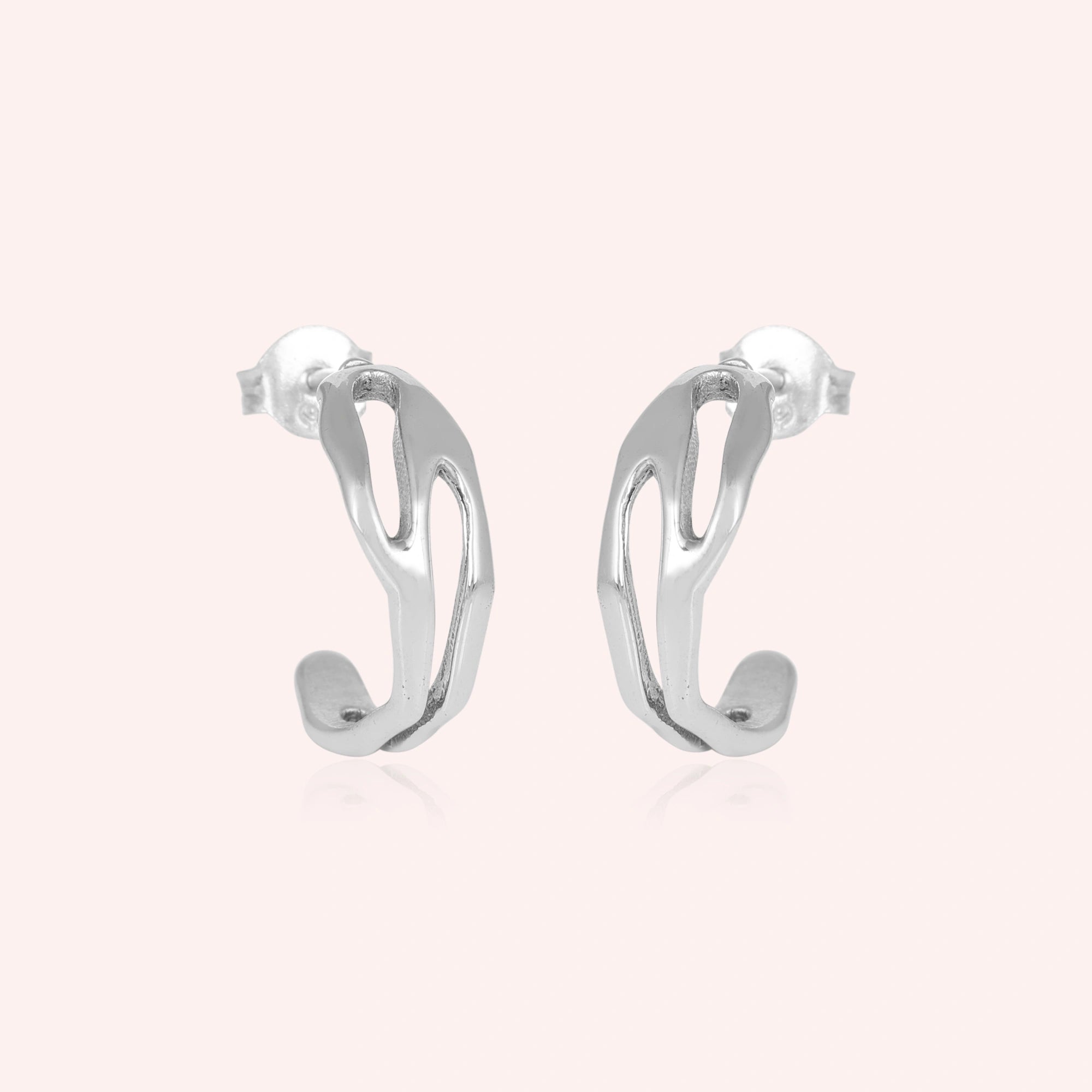 Silver hoop earrings shown at front angled view featuring sleek sculpted open hoops in polished silver against pink background
