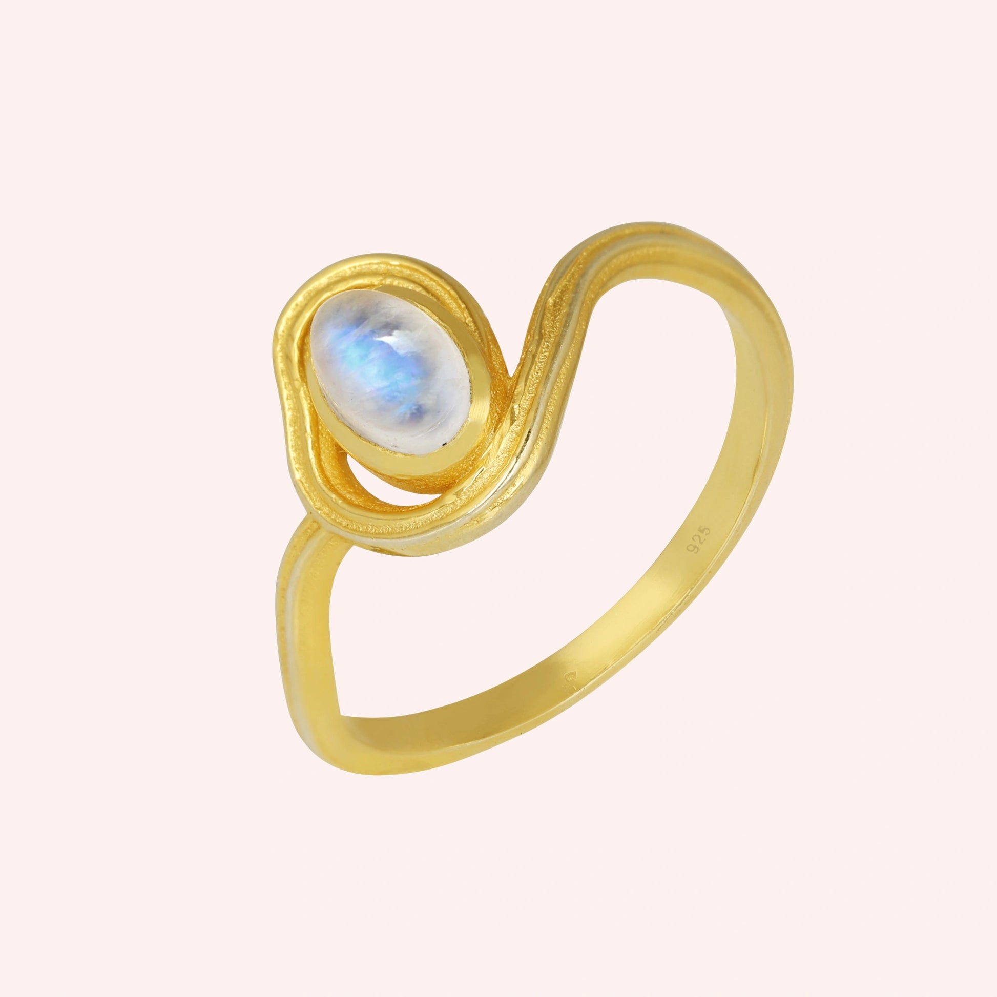 Moonstone_ring_with_gold_plated_silver_wave_band_at_side_angle_on_solid_pink_background