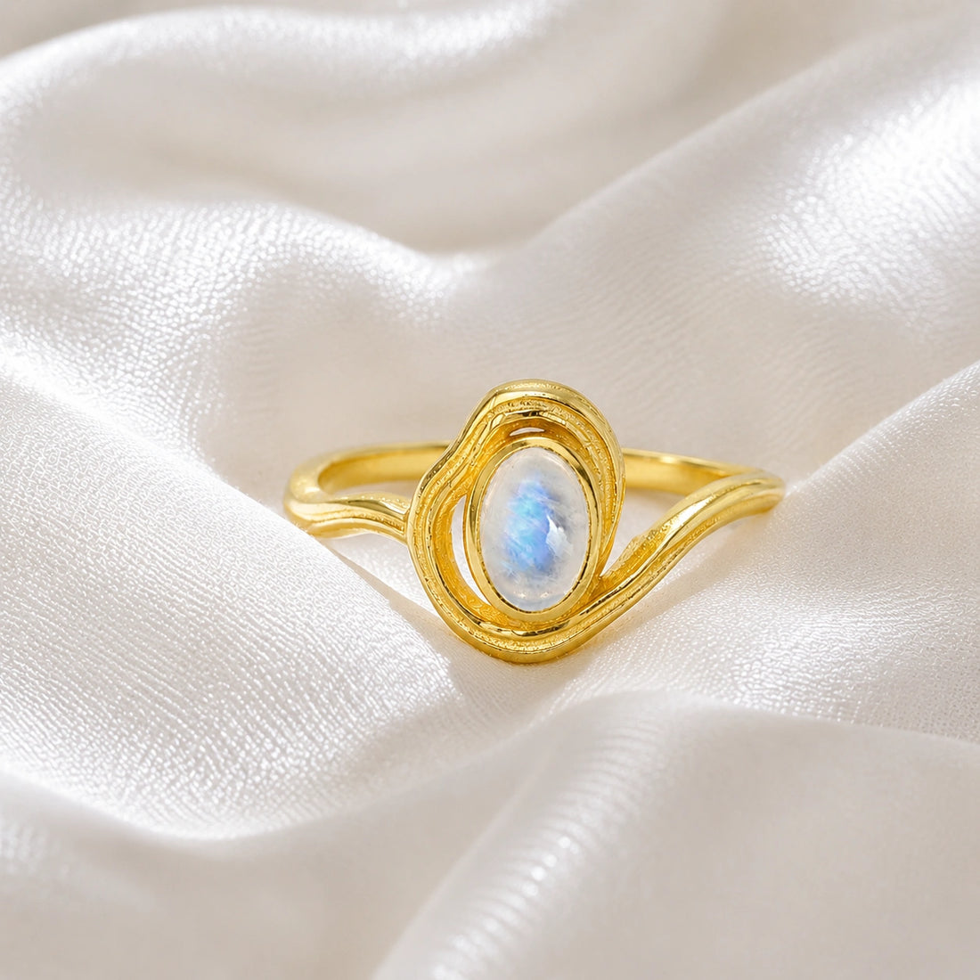 Moonstone_ring_with_gold_plated_silver_wave_band_at_front_angle_on_soft_fabric_background