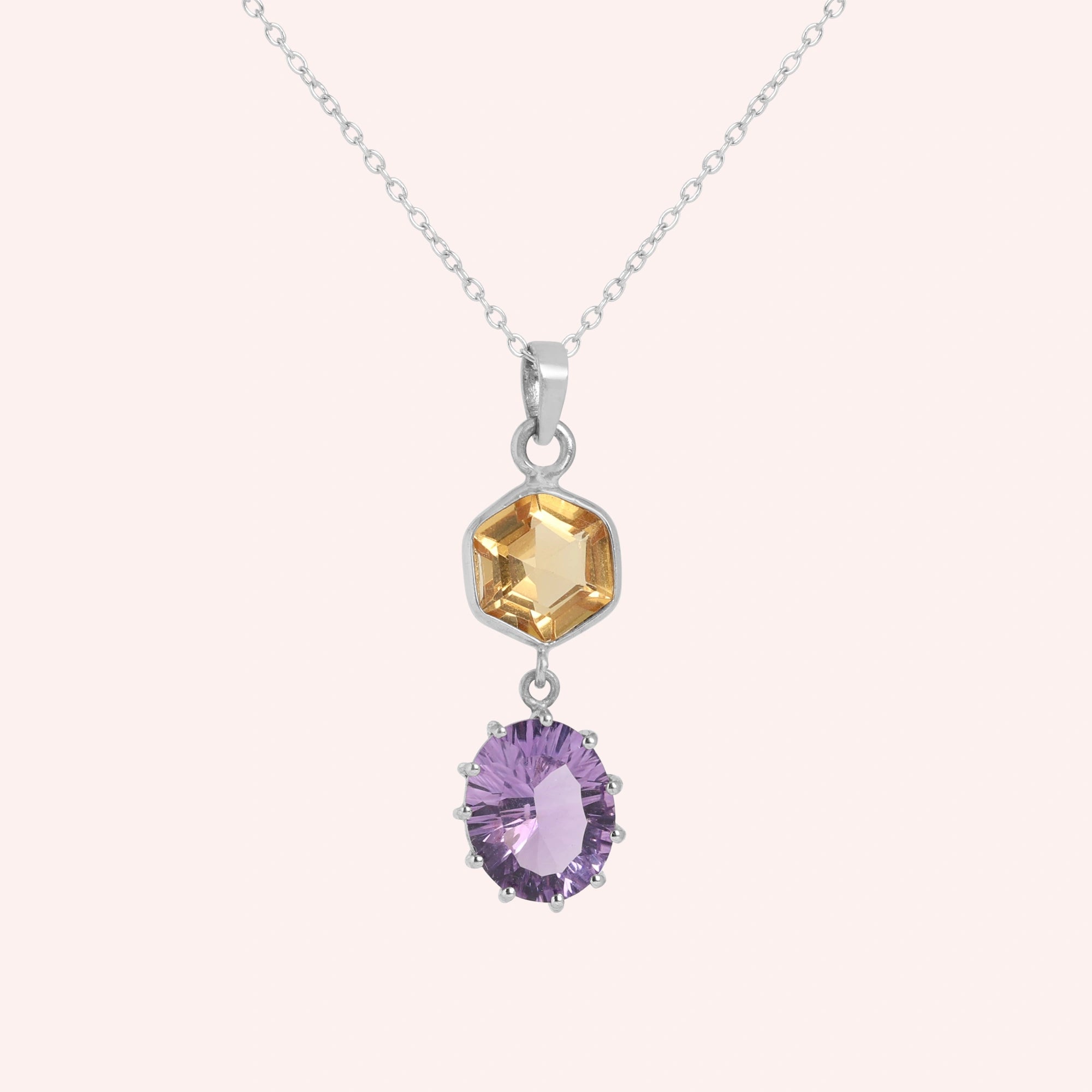 Silver_pendant_necklace_with_amethyst_and_citrine_stones_in_sterling_silver_at_front_angle_view_on_solid_pink_background