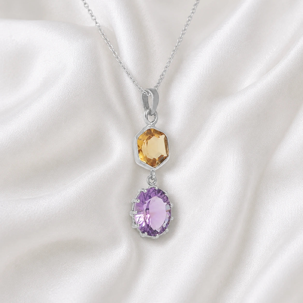 Silver_pendant_necklace_with_amethyst_and_citrine_stones_in_sterling_silver_at_slight_angle_view_on_soft_fabric_background